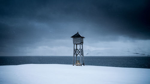 Lighthouse by sea against sky at night