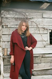 Portrait of young woman standing against house