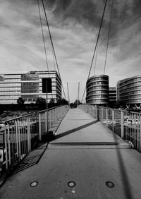 Footbridge amidst buildings in city against sky