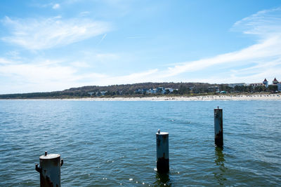 Wooden posts in sea against sky