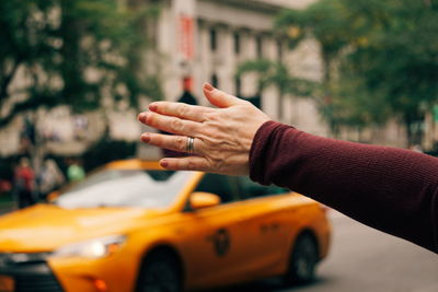 Cropped hand of woman hitchhiking on road