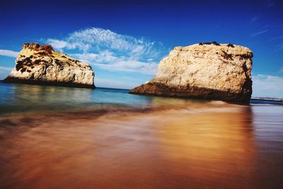 Rock formations in sea against blue sky