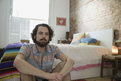 Young man sitting beside his bed