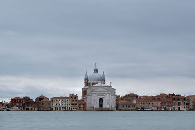 Buildings at waterfront in venice against cloudy sky