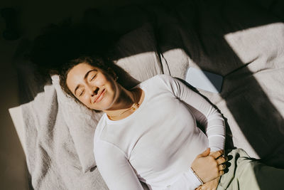 Directly above shot of young woman lying on bed at home