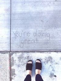 Low section of woman standing by text on footpath