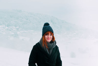 Portrait of smiling young woman standing in snow