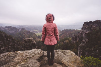 Full length of woman looking at view while standing on rock