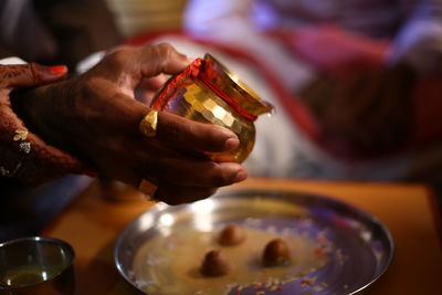 Midsection of person holding and poring water on god statue ritual in indian wedding