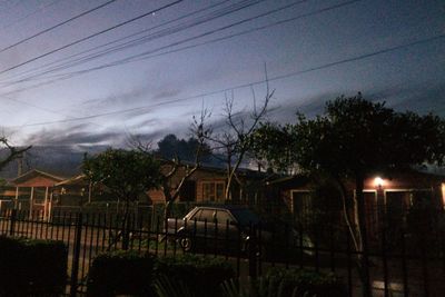 Trees and buildings against sky at dusk