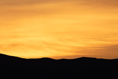 Scenic view of silhouette mountains against orange sky