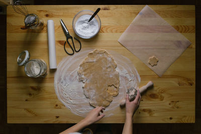 Top view of a young woman making christmas cookies on a wooden table