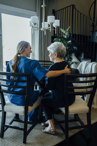 Rear view of senior woman and home caregiver sitting at dining table