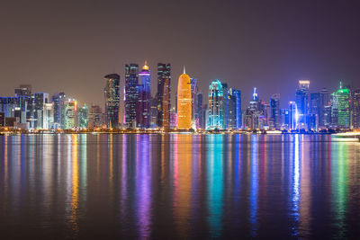 Illuminated buildings of doha city against sky at night