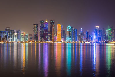 Illuminated buildings of doha city against sky at night