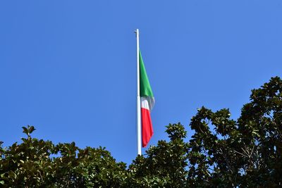 Low angle view of flags against clear blue sky