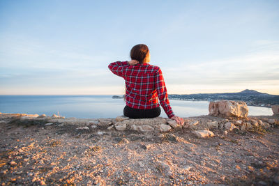 Rear view of man looking at sea against sky