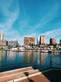 Boats moored at harbor against buildings in city