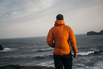 Youngman standing at windy beach of dyrhólaey, iceland