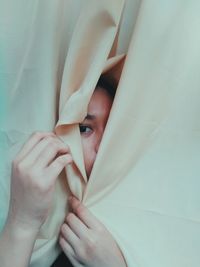 Close-up portrait of woman by curtain