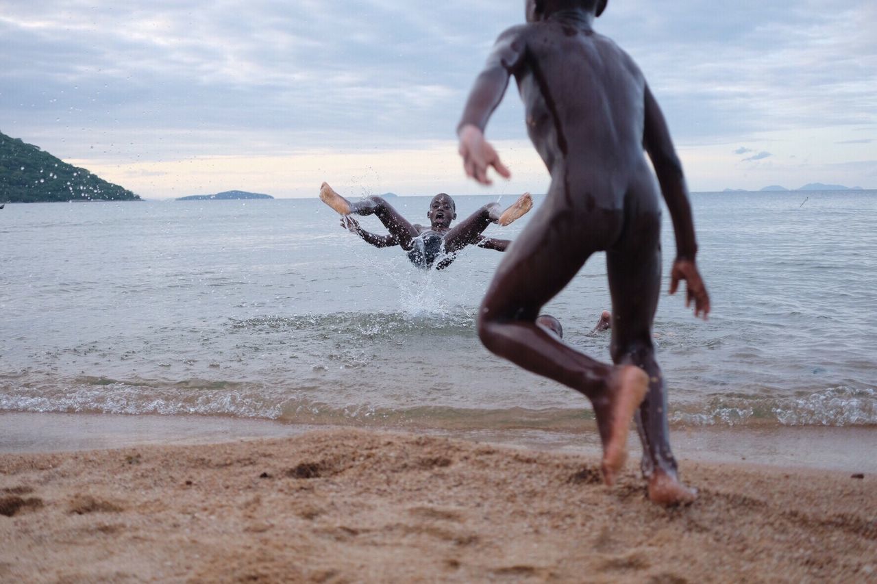 sea, water, sky, beach, horizon over water, full length, shore, men, leisure activity, sand, nature, cloud - sky, lifestyles, beauty in nature, motion, cloud, jumping, tranquility