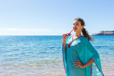 Woman standing at sea shore against sky