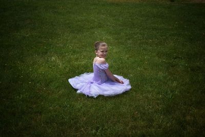 High angle portrait of girl wearing purple tutu while sitting on grassy field