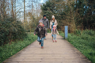 Rear view of friends standing on footpath amidst trees