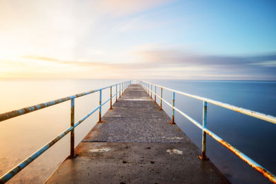 Stone jetty with railing leading into the sea, madeira.