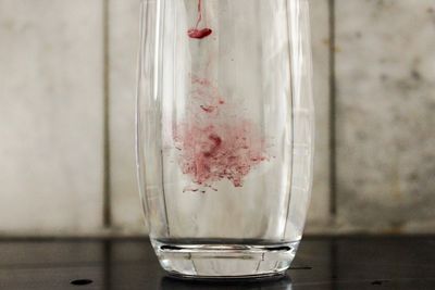 Close-up of red color dissolving in water on table