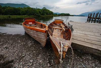 Boat moored on lake against sky
