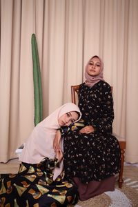 Portrait of sisters wearing hijabs while sitting at home