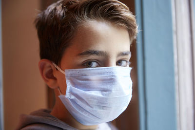 Close-up portrait of boy wearing mask at home