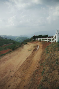 Road amidst field against sky