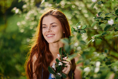 Portrait of young woman standing amidst plants