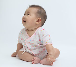 Cute boy looking away against white background