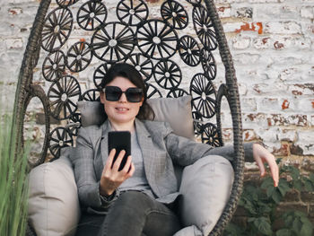 A young beautiful caucasian girl holds a phone in her hands and looks at the smartphone screen