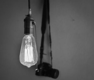 Low angle view of illuminated light bulb against wall