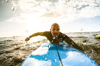 Mature man surfing in sea against sky