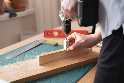 Drilling a hole in a tree with a metal drill on wood, the theme of craft and woodworking