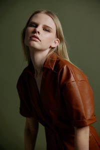 Portrait of young woman standing against wall