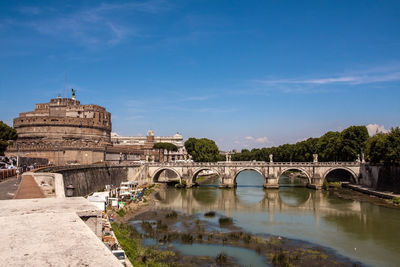 Arch bridge over river against blue sky