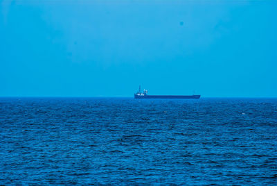 Boat sailing in sea against clear blue sky