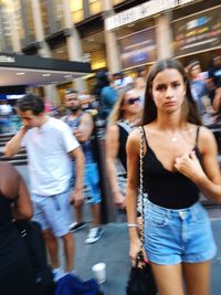 Portrait of young woman standing on city street