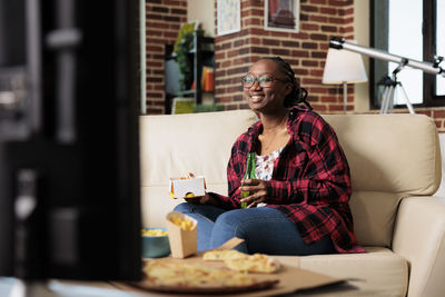 Smiling woman with fast food watching movie at home