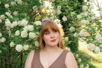 Portrait of beautiful young woman against plants