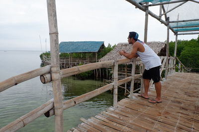 Side view of man standing on pier over sea against sky