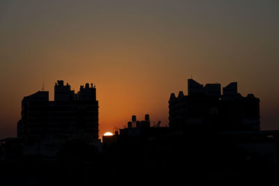 Silhouette buildings against sky during sunset