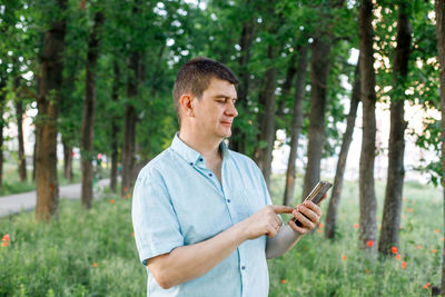 Young man using mobile phone in forest