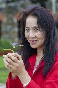 Portrait of woman holding red flower